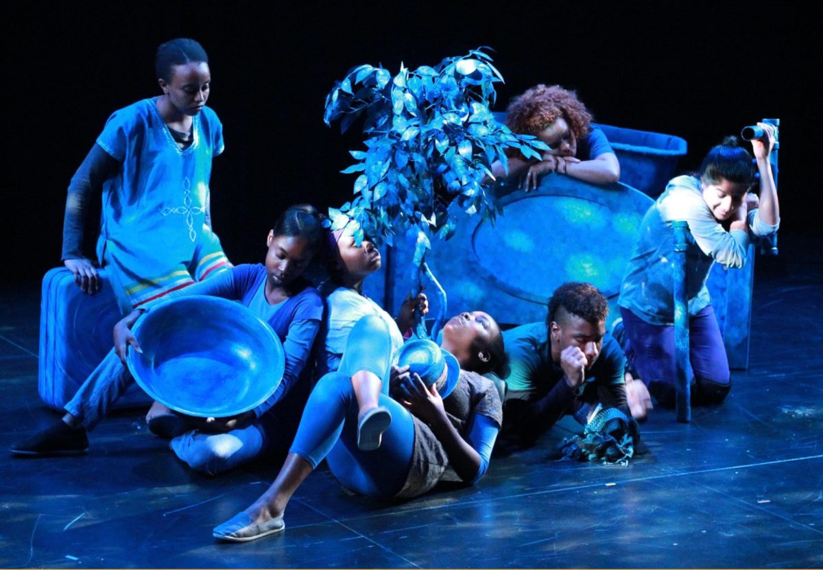 Youth onstage performing with blue stage lights, some lying down some sitting, as part of a show about the school to prison pipeline